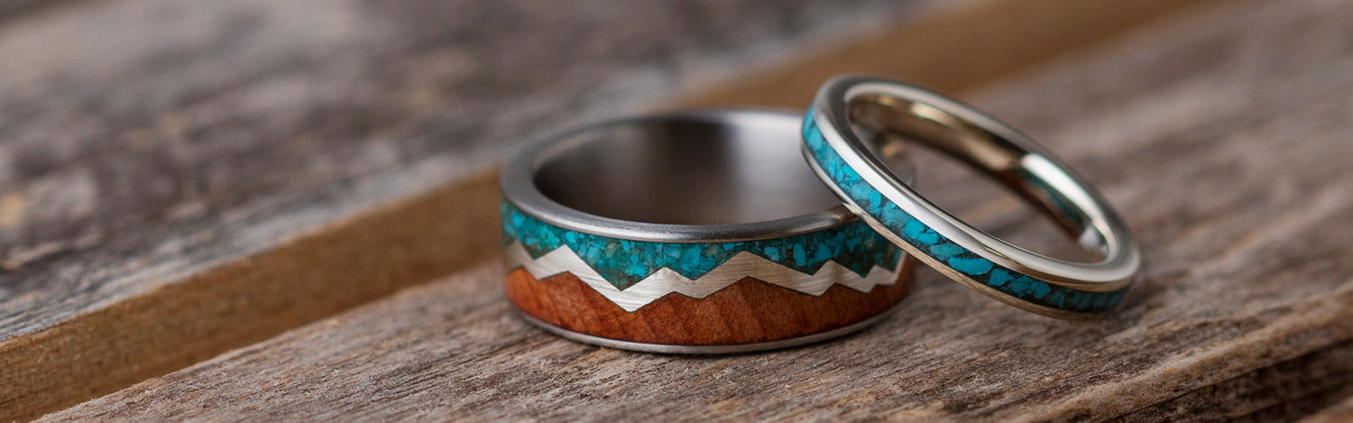 Handcrafted silver and turquoise rings displayed on a wooden surface, showcasing intricate designs and vibrant blue-green turquoise gemstones.