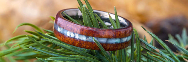 A wooden ring resting on green pine needles.