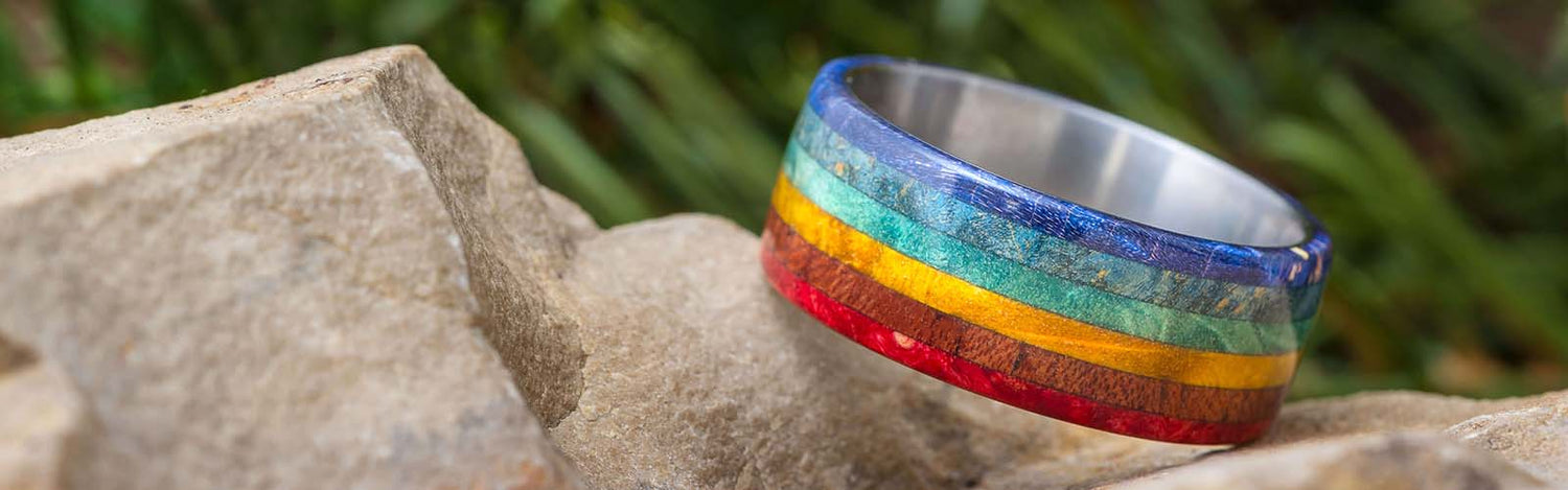 Vibrant rainbow jewelry ring with colorful wood inlays on rocks.