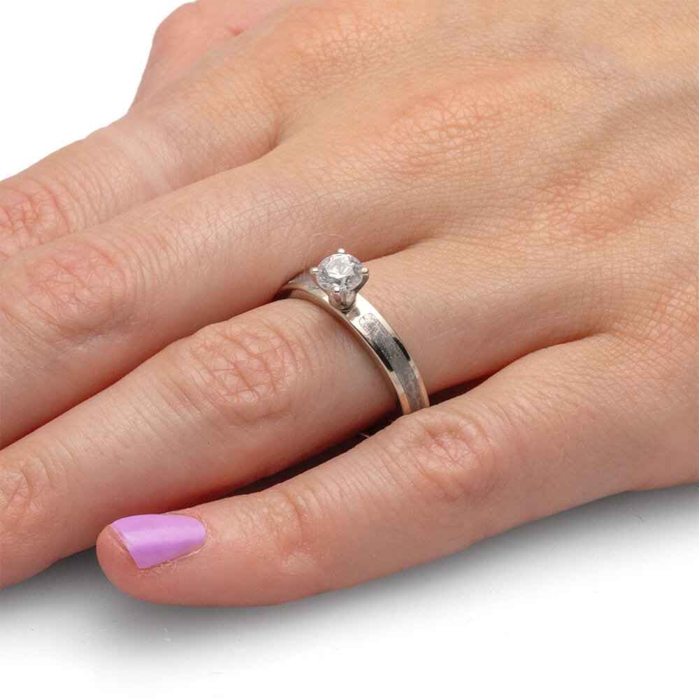 Hand wearing a 0.5-carat diamond ring with a simple silver band.