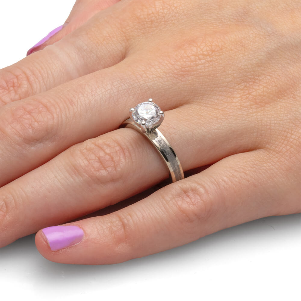 Hand wearing a 1.5-carat diamond ring with a simple silver band.