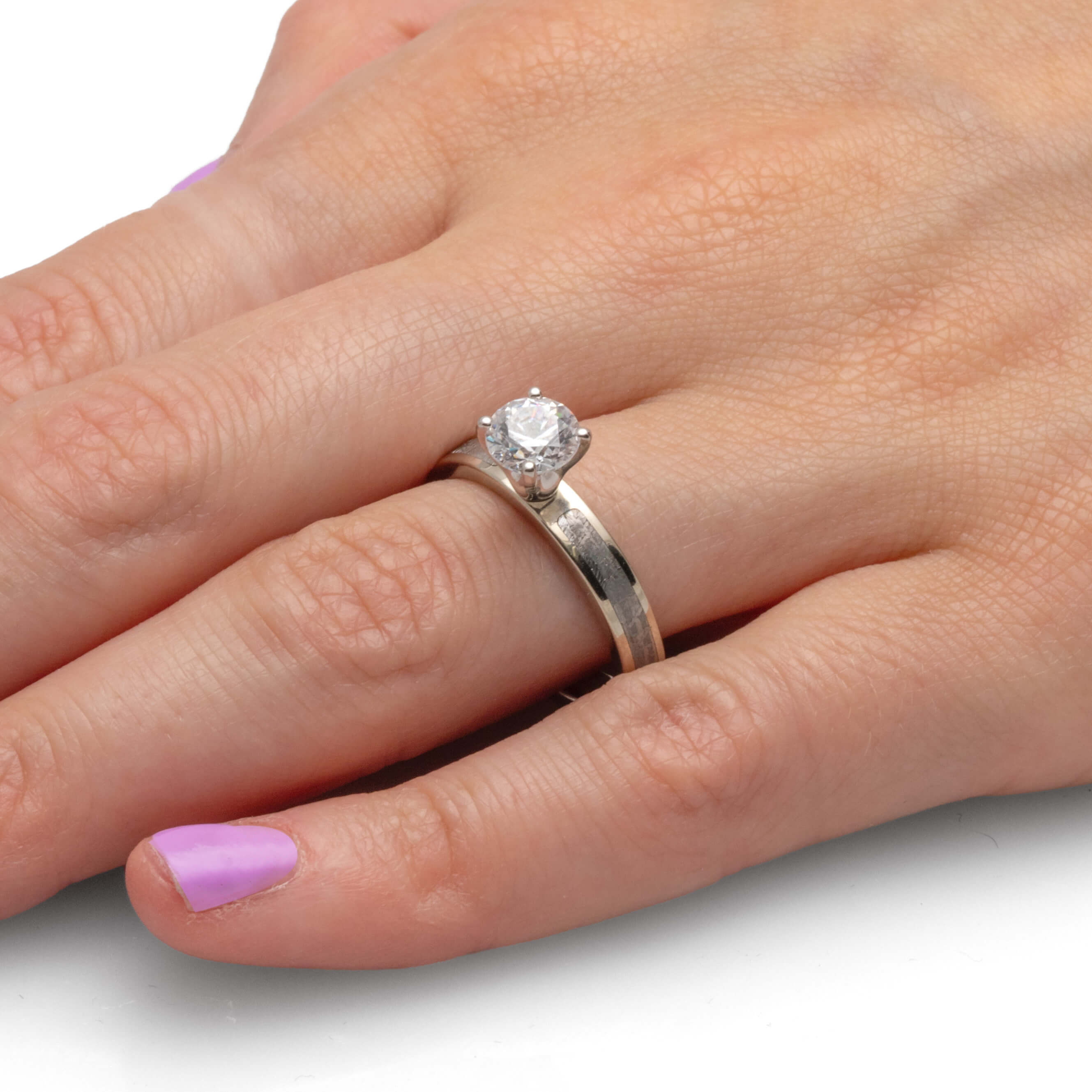 Hand wearing a 1-carat diamond ring with a simple silver band.