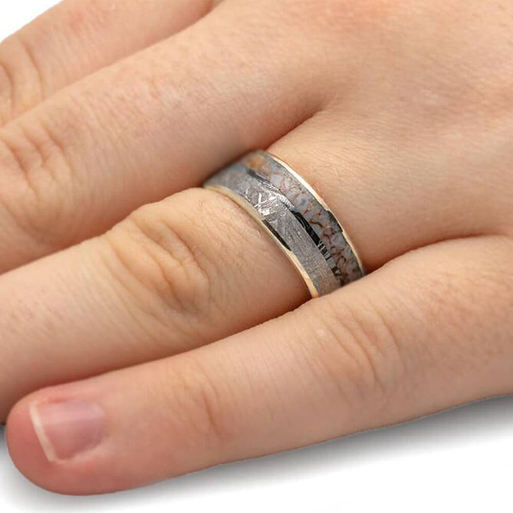 White gold ring with meteorite and dino bone on finger