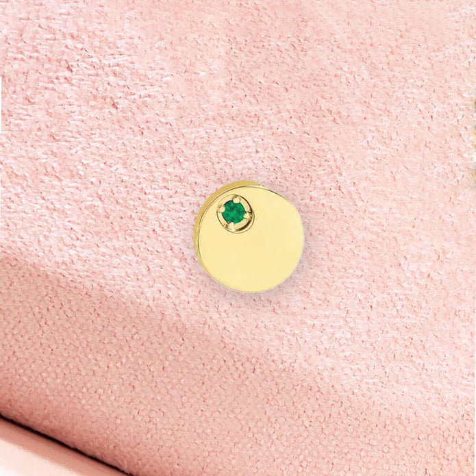 Close-up of emerald circle pendant on pink fabric