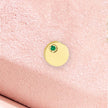 Close-up of emerald circle pendant on pink fabric