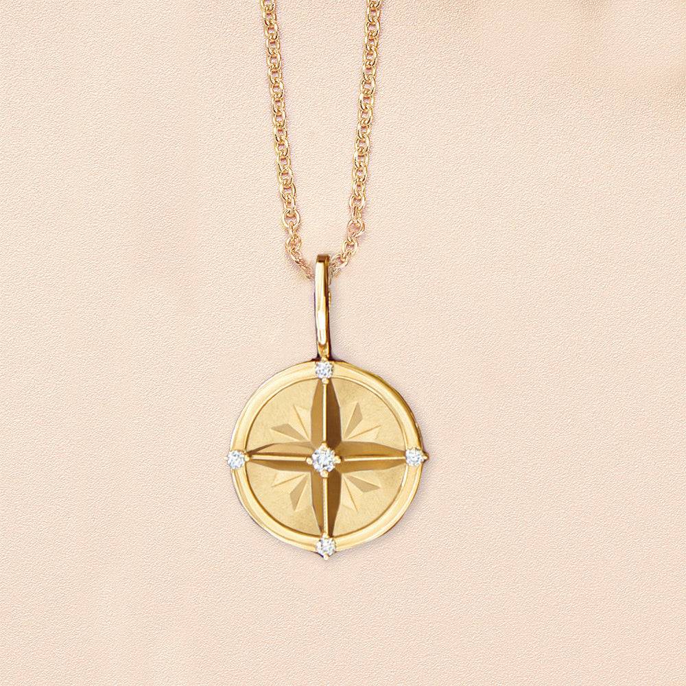 Gold compass necklace with natural diamonds on display