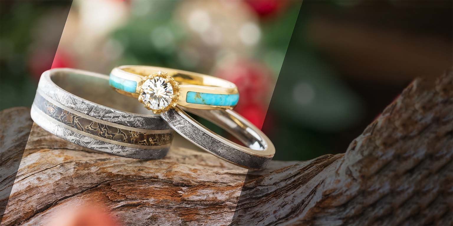 Two rings, one gold and silver with turquoise stones, on a wooden surface.
