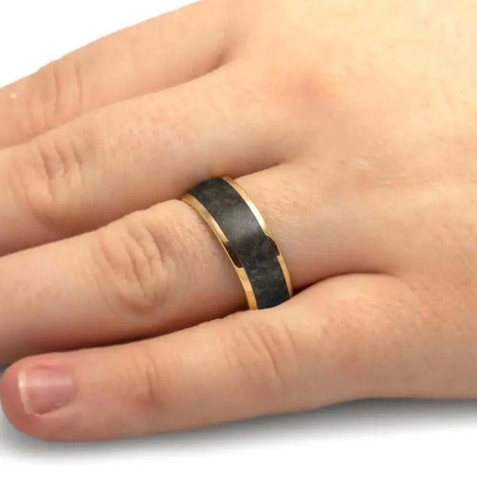 Hand wearing a black and gold ring on a white background