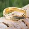 Gold wedding band with meteorite inlay and diamond twist set on a birch wood background. Features polished 14k yellow gold and Gibeon meteorite.
