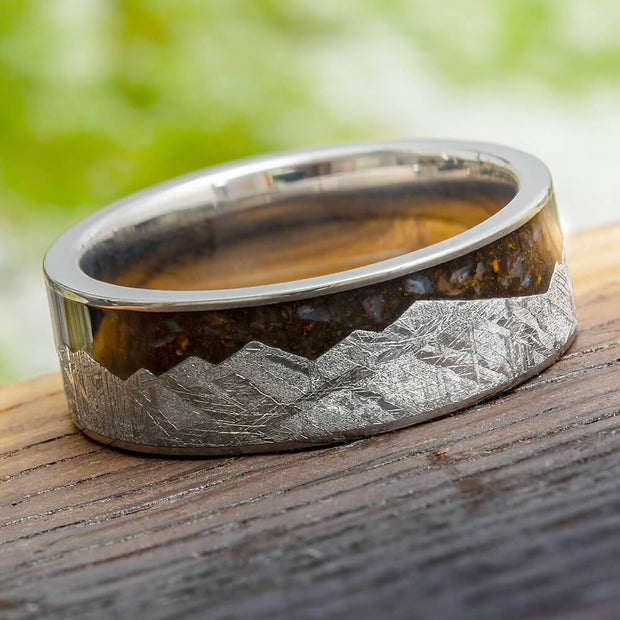 Meteorite mountain ring with dinosaur bone on wood