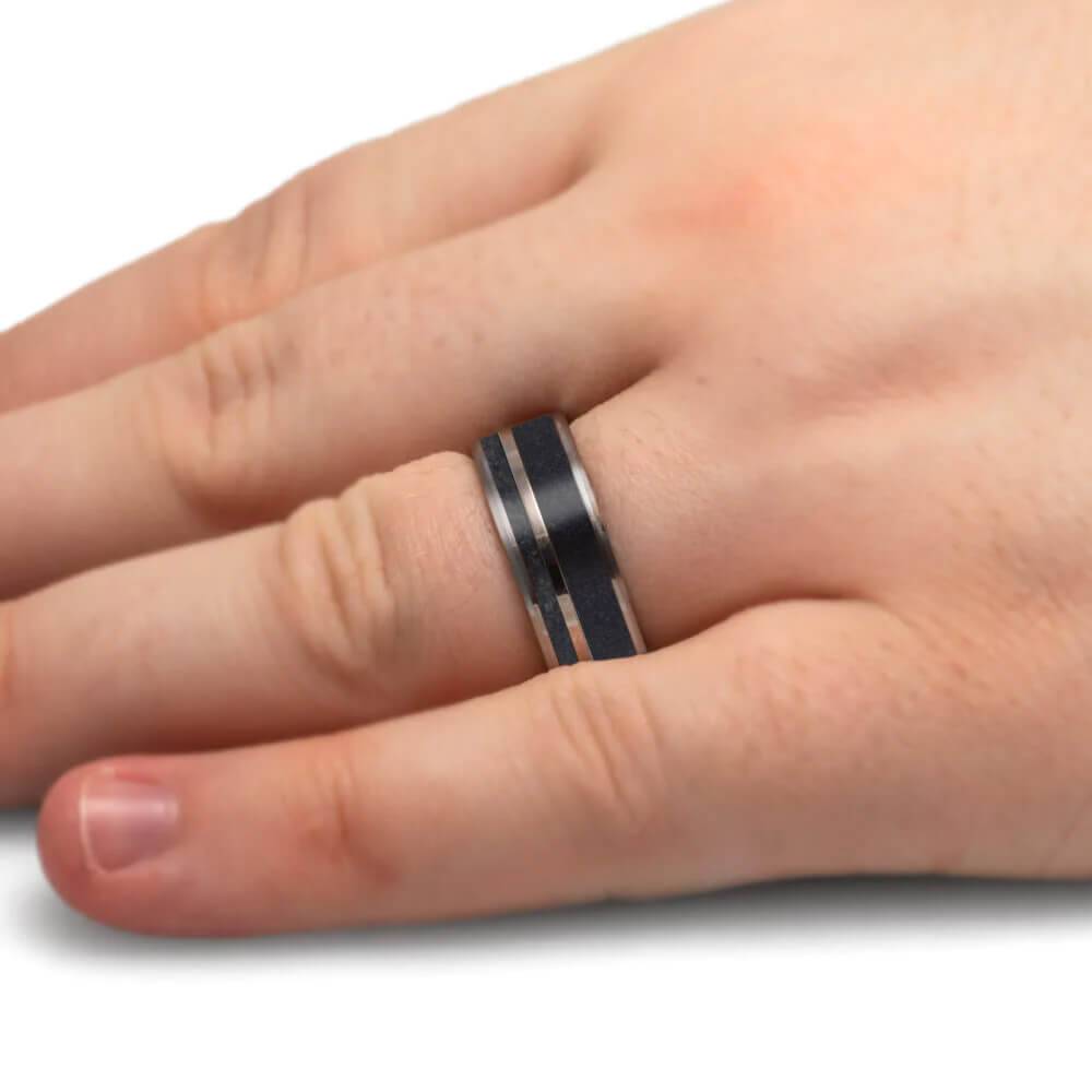 Titanium wedding band with dark inlay worn on a finger.