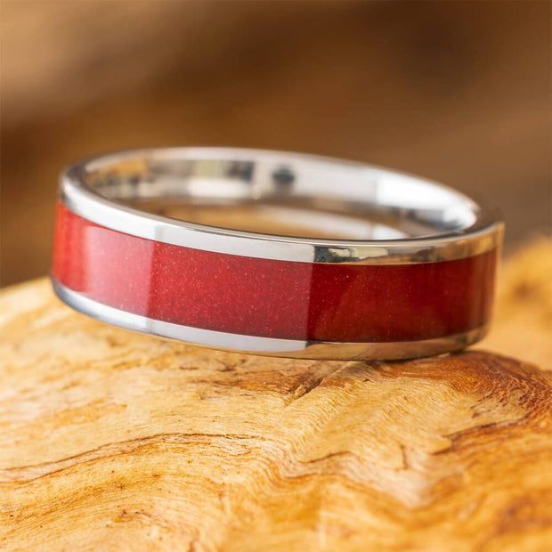 Red sand titanium wedding band on wood surface