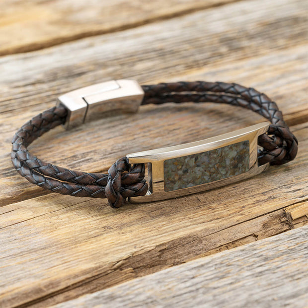 Bracelet with braided brown leather strap on a wooden surface