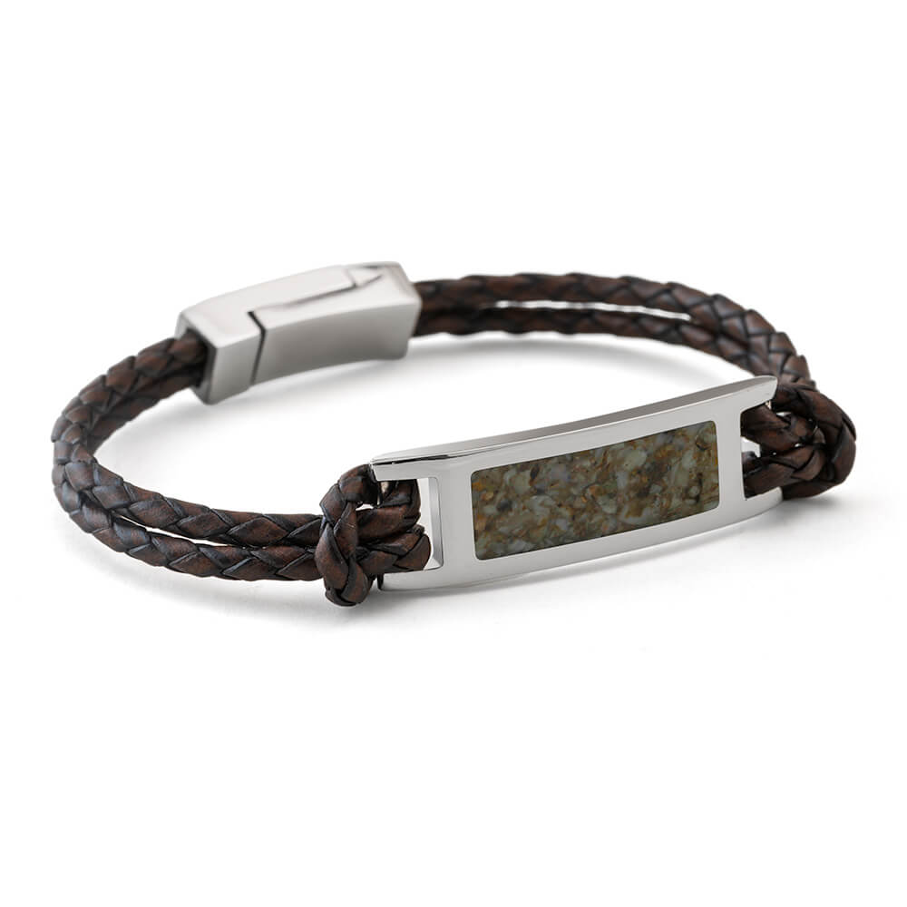 Brown braided leather bracelet with a metal tag on a white background
