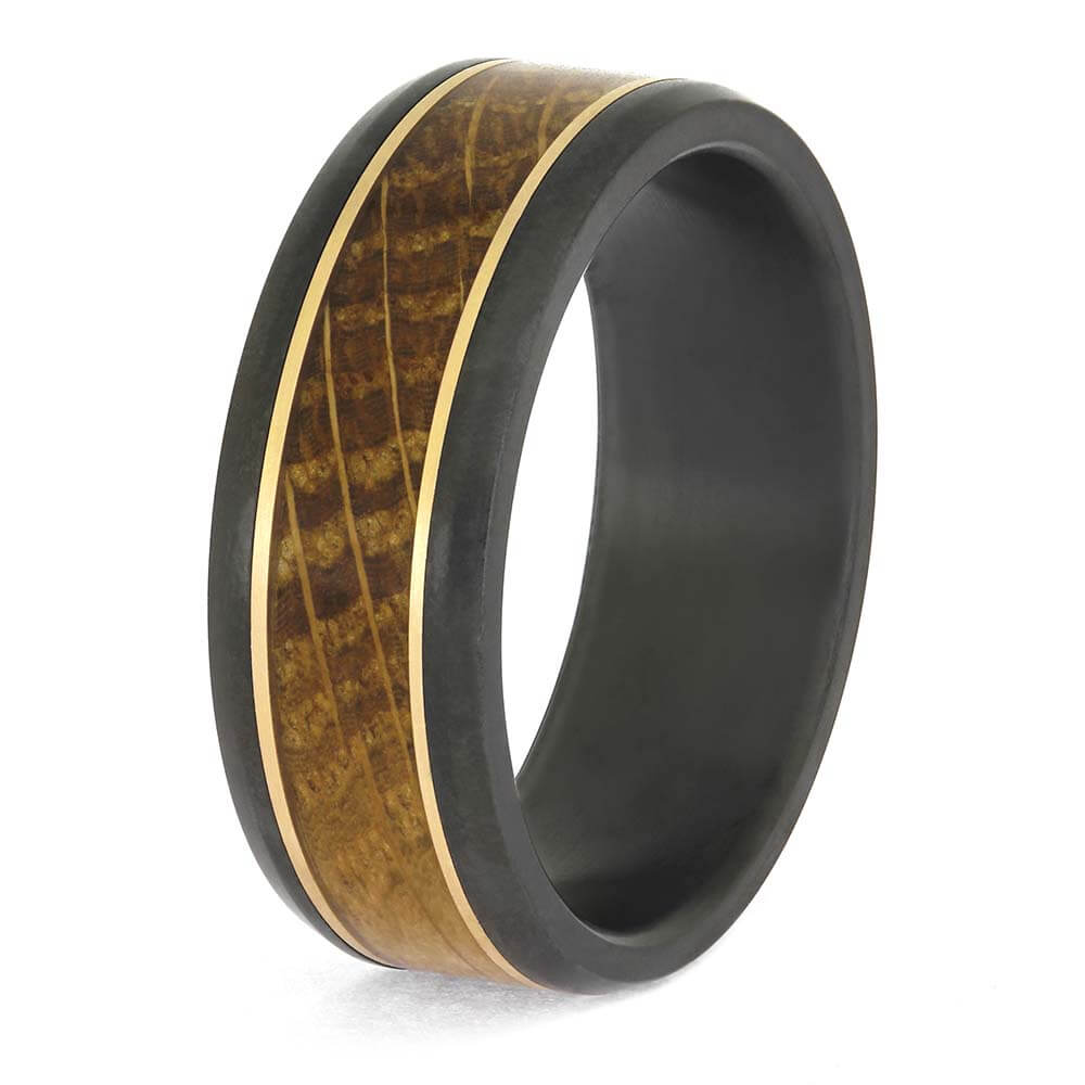 Stylish gold and black zirconium wedding band for men, featuring a diagonal whiskey oak inlay and polished gold trim, shown in a standing position.