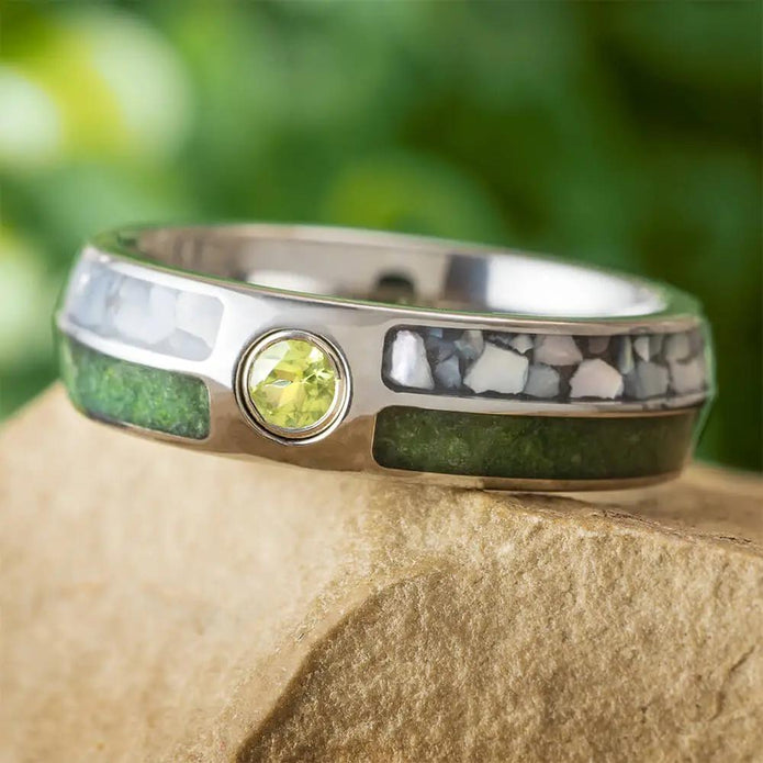 Colorful birthstone wedding band with crushed peridot and pearl inlays, featuring a bezel-set peridot on a titanium ring with polished finish.