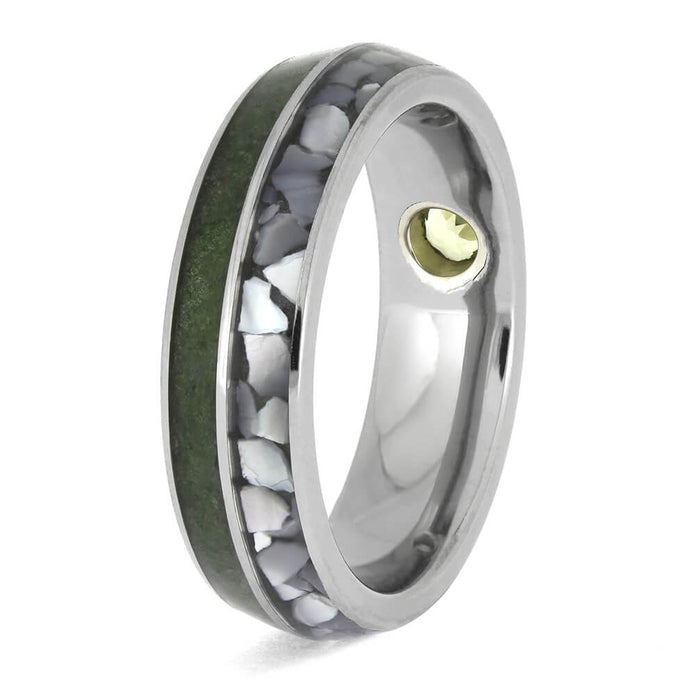 Custom titanium ring with dual inlays of green peridot and white pearl, accented by a recessed bezel-set peridot gemstone.