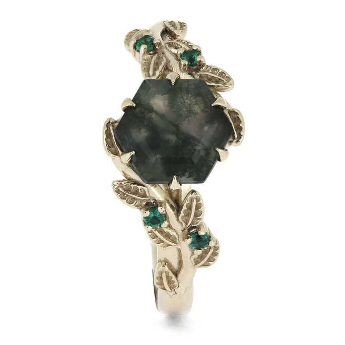 Gold ring with a large green gemstone and smaller green stones on a white background