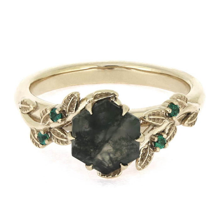 Gold ring with a central black stone and green gemstones on a white background