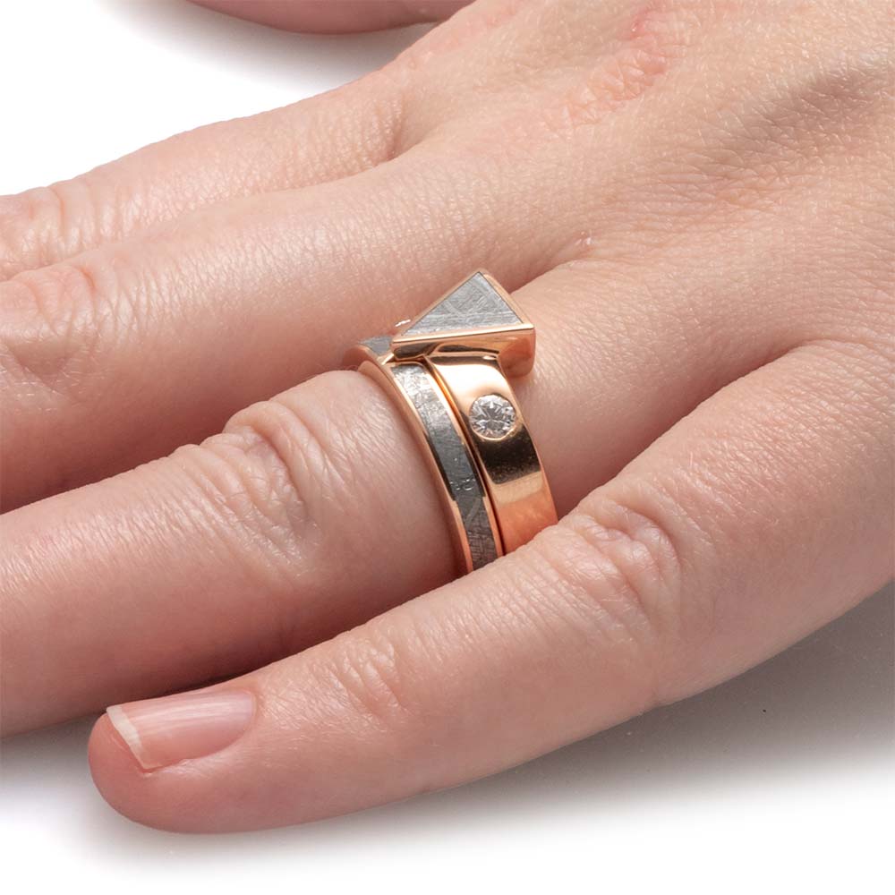 Rose gold ring with a diamond on a finger against a white background