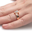 Rose gold ring with a diamond on a finger against a white background