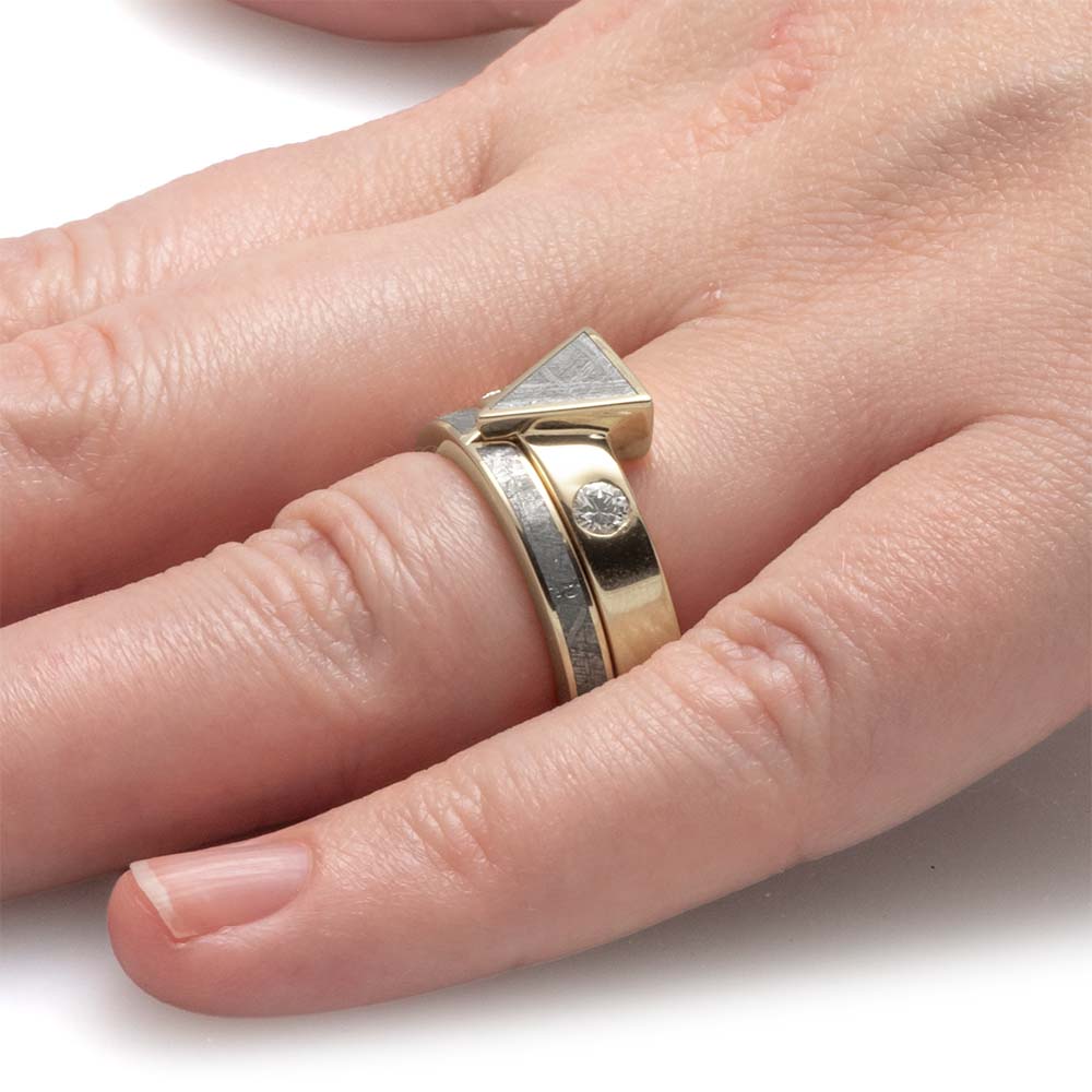 Gold ring with a diamond on a finger against a white background