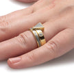Gold ring with geometric design on a finger against a white background