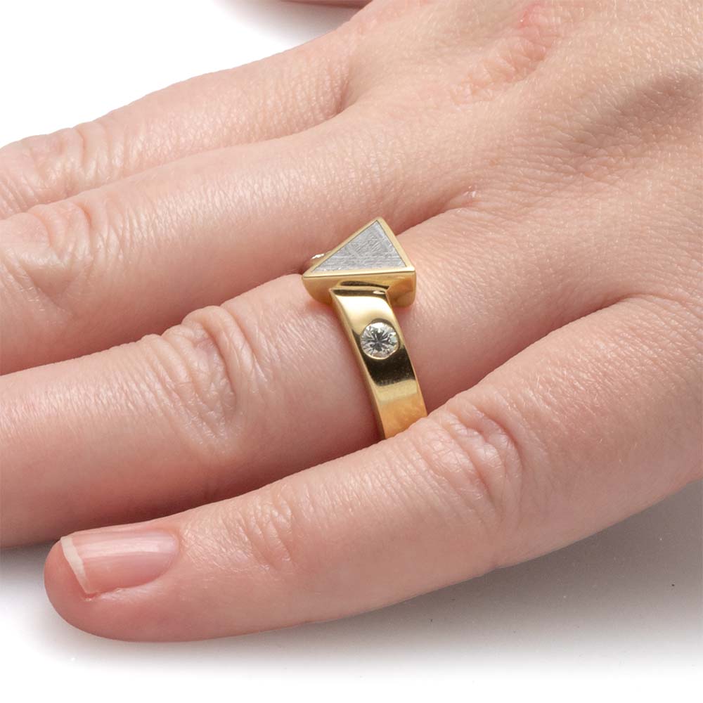 Gold ring with a diamond on a person's finger against a white background