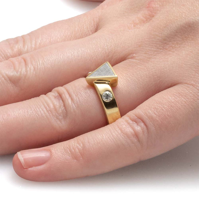Gold ring with a diamond on a person's finger against a white background