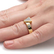 Gold ring with a diamond on a person's finger against a white background