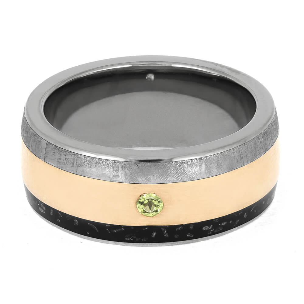 Flat-lay view of meteorite wedding band with rose gold, stardust inlay, and peridot stone. Men's triple inlay ring with cosmic elegance.