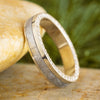 Two gold rings with diamond accents on a stone surface