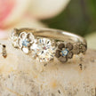 Silver ring with floral designs and gemstones on a stone surface