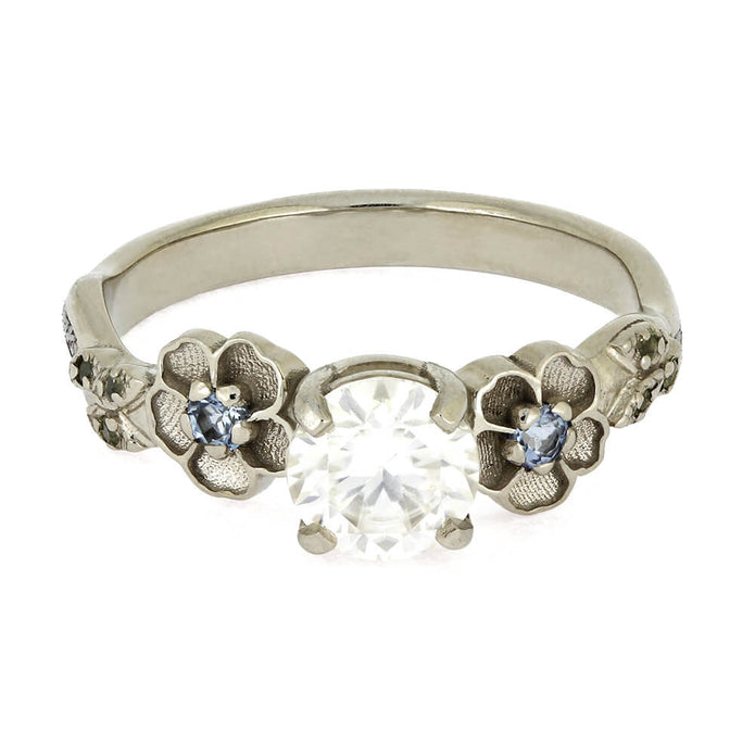 Silver ring with floral design and gemstones on a white background