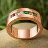 Rose gold ring with gemstones on a stone surface with a blurred green background