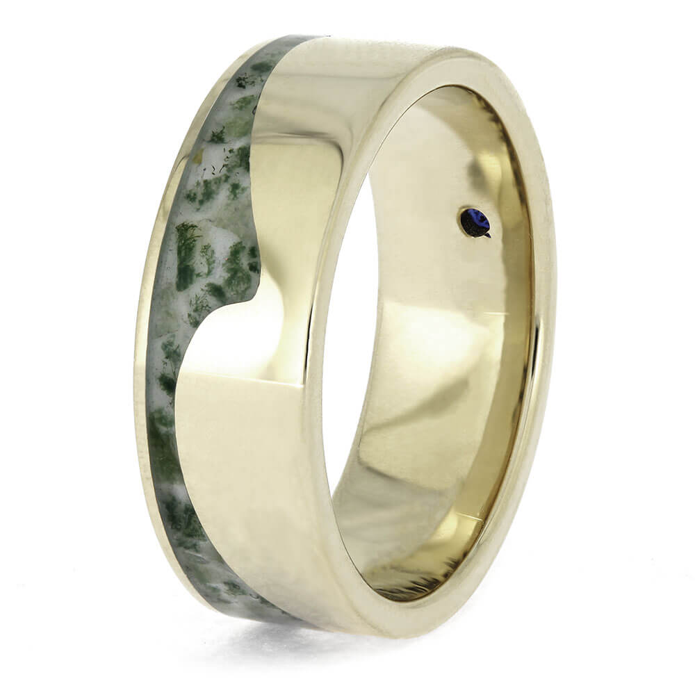 Gold ring with green stone inlay on a white background