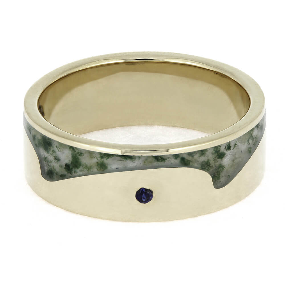 Gold ring with a green stone and a small purple gemstone on a white background
