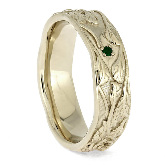 Gold ring with intricate design and a green gemstone on a white background