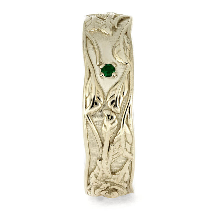 Gold ring with intricate design and a green gemstone on a white background