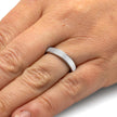 Silver ring on a person's finger with a plain background
