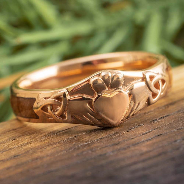 Rose gold ring with heart design on a wooden surface
