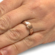 Rose gold ring with a foot design on a hand against a white background