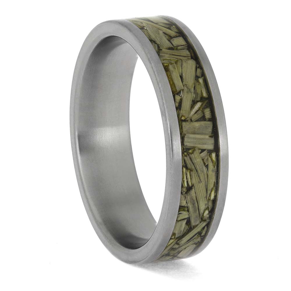 Silver ring with embedded green material on a white background