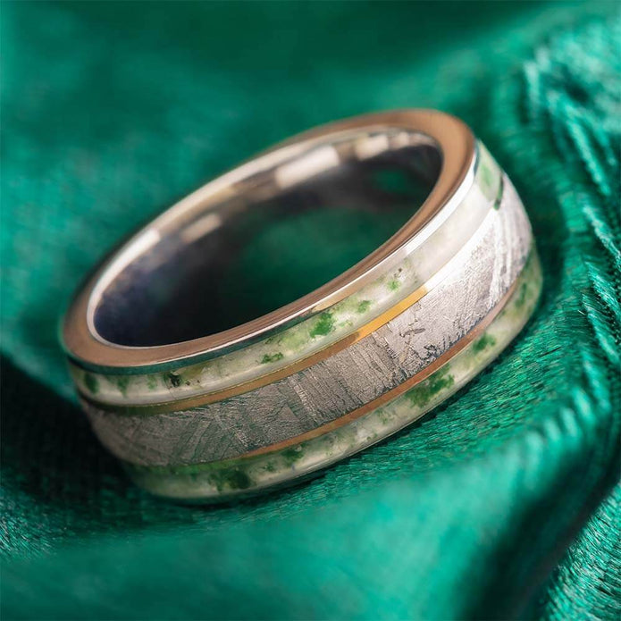 Silver ring with green inlay on a green fabric background