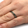 Silver ring on a person's finger with a plain background
