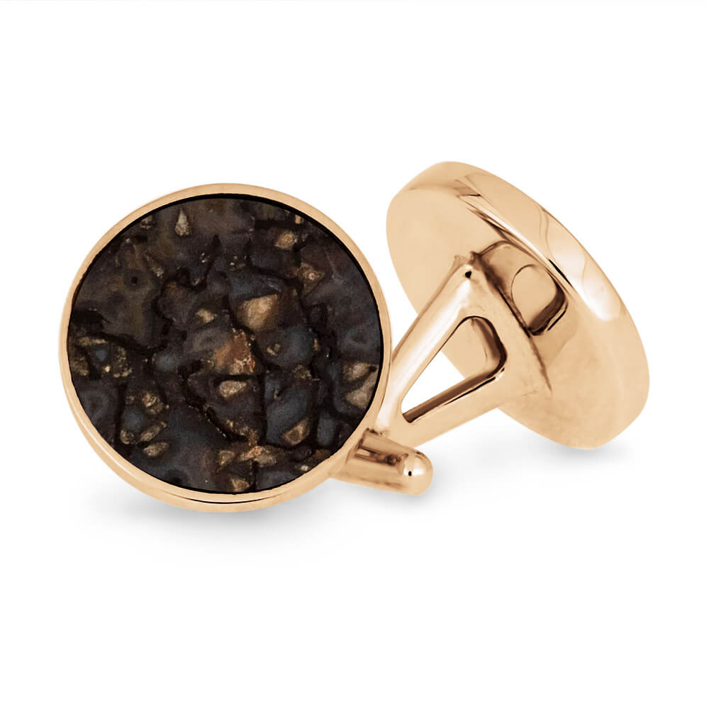 Gold cufflinks with a dark stone design on a white background
