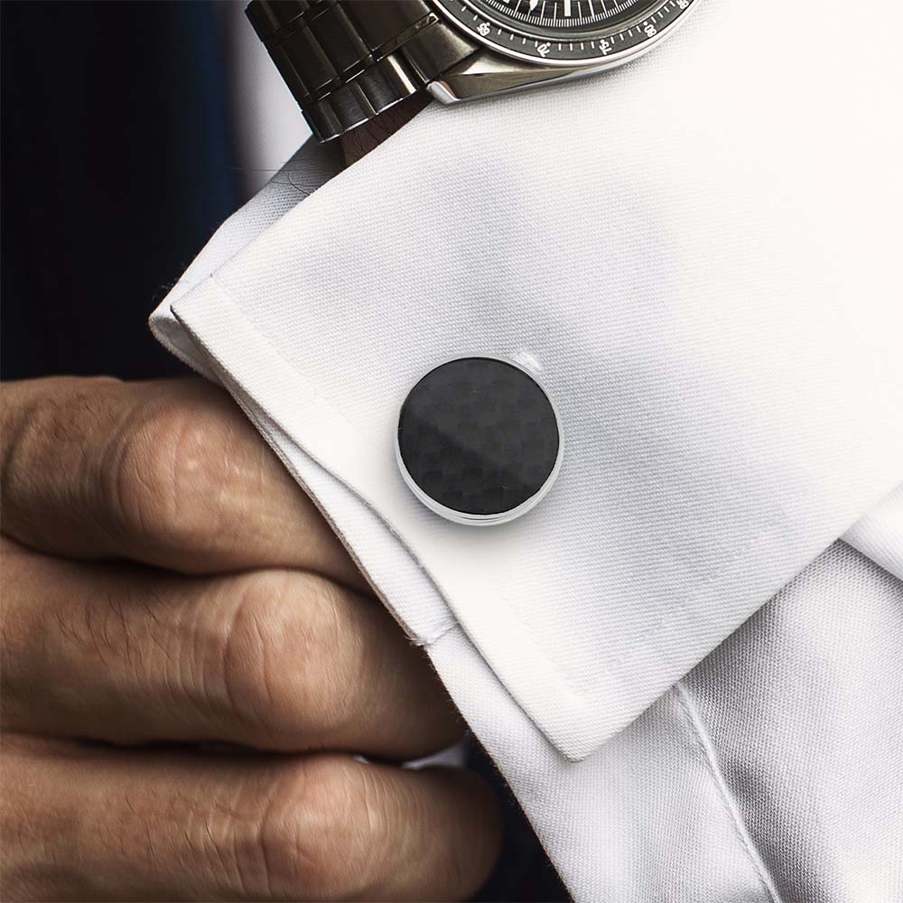 Black cufflinks being worn on a white shirt with a watch on the wrist.