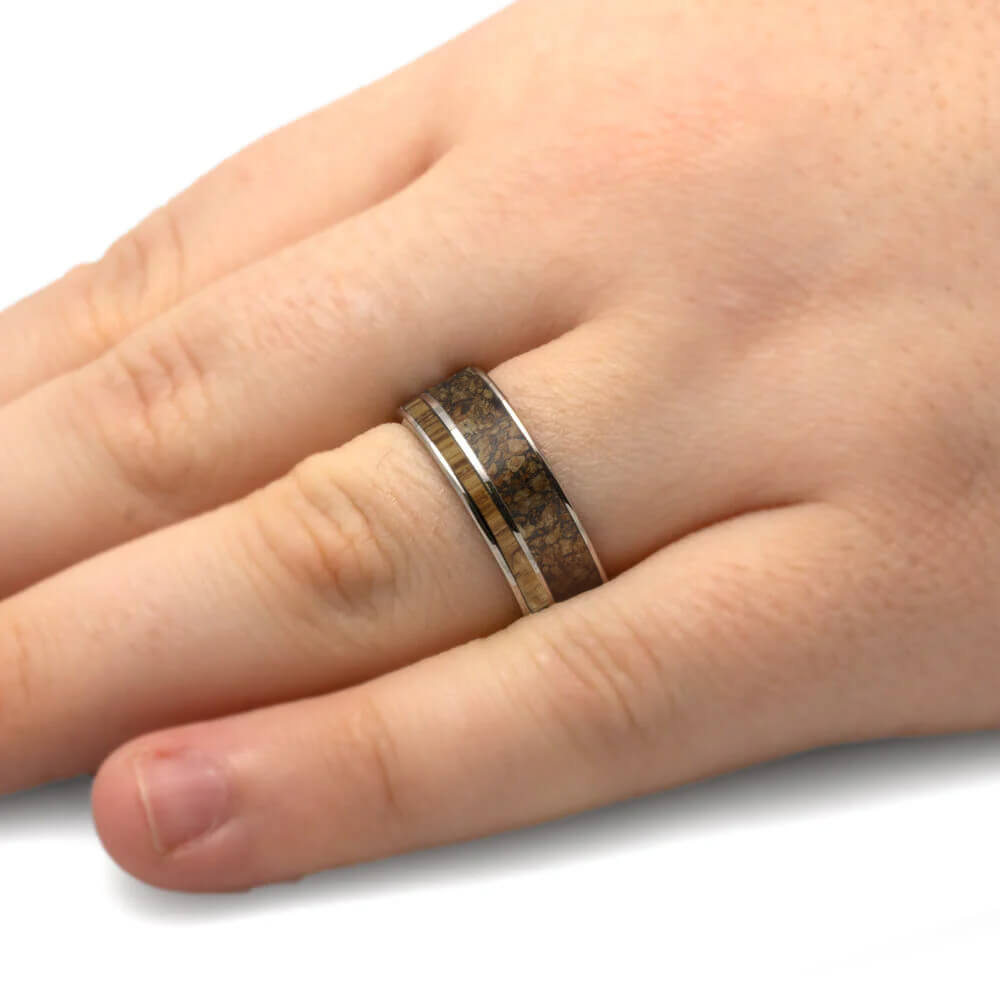 Hand wearing a ring with a textured band on a white background