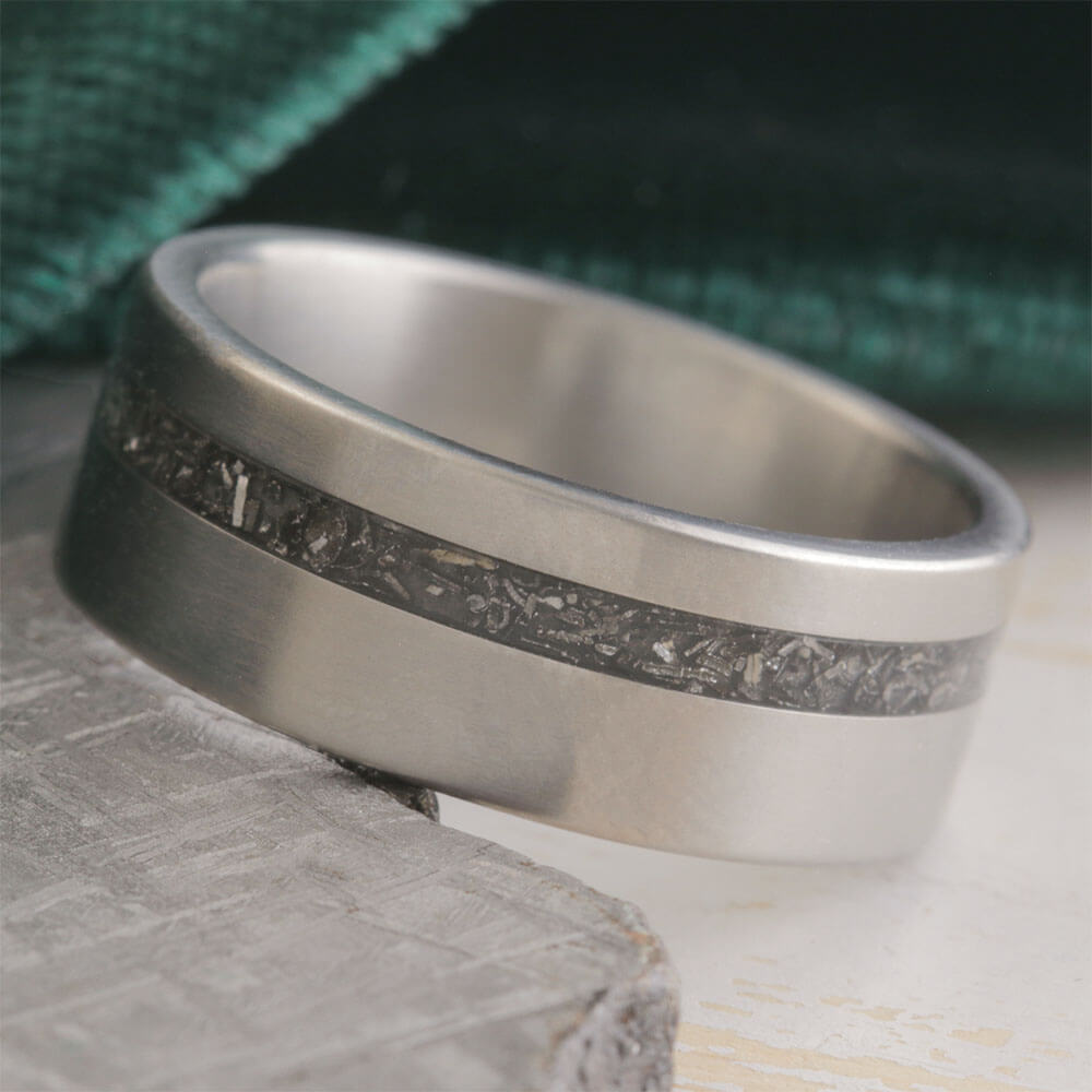 Silver ring with a textured band on a stone surface