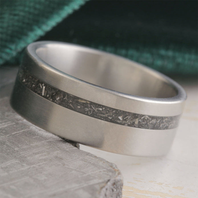 Silver ring with a textured band on a stone surface